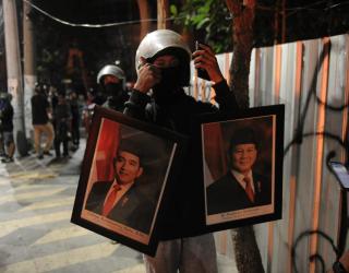 Seorang penjarah membawa bingkai foto Presiden dan Wakil Presiden dari dalam gedung yang dirusak massa saat kericuhan di Surabaya, Sabtu (30/8/2025) malam. (Sumber Foto: Julian)