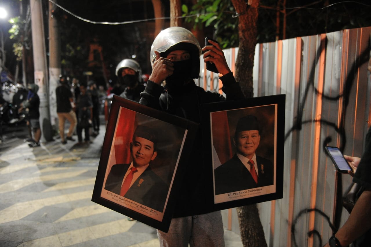 Seorang penjarah membawa bingkai foto Presiden dan Wakil Presiden dari dalam gedung yang dirusak massa saat kericuhan di Surabaya, Sabtu (30/8/2025) malam. (Sumber Foto: Julian)