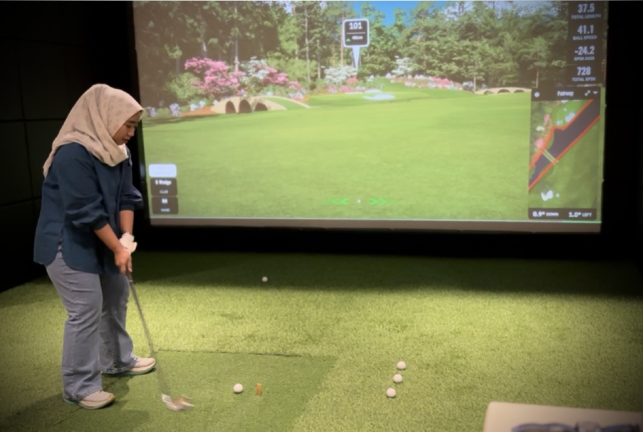Sekar saat mencoba pengalaman bermain dengan golf simulator di Brawijaya Driving Range. (Foto: Ardhia tap)