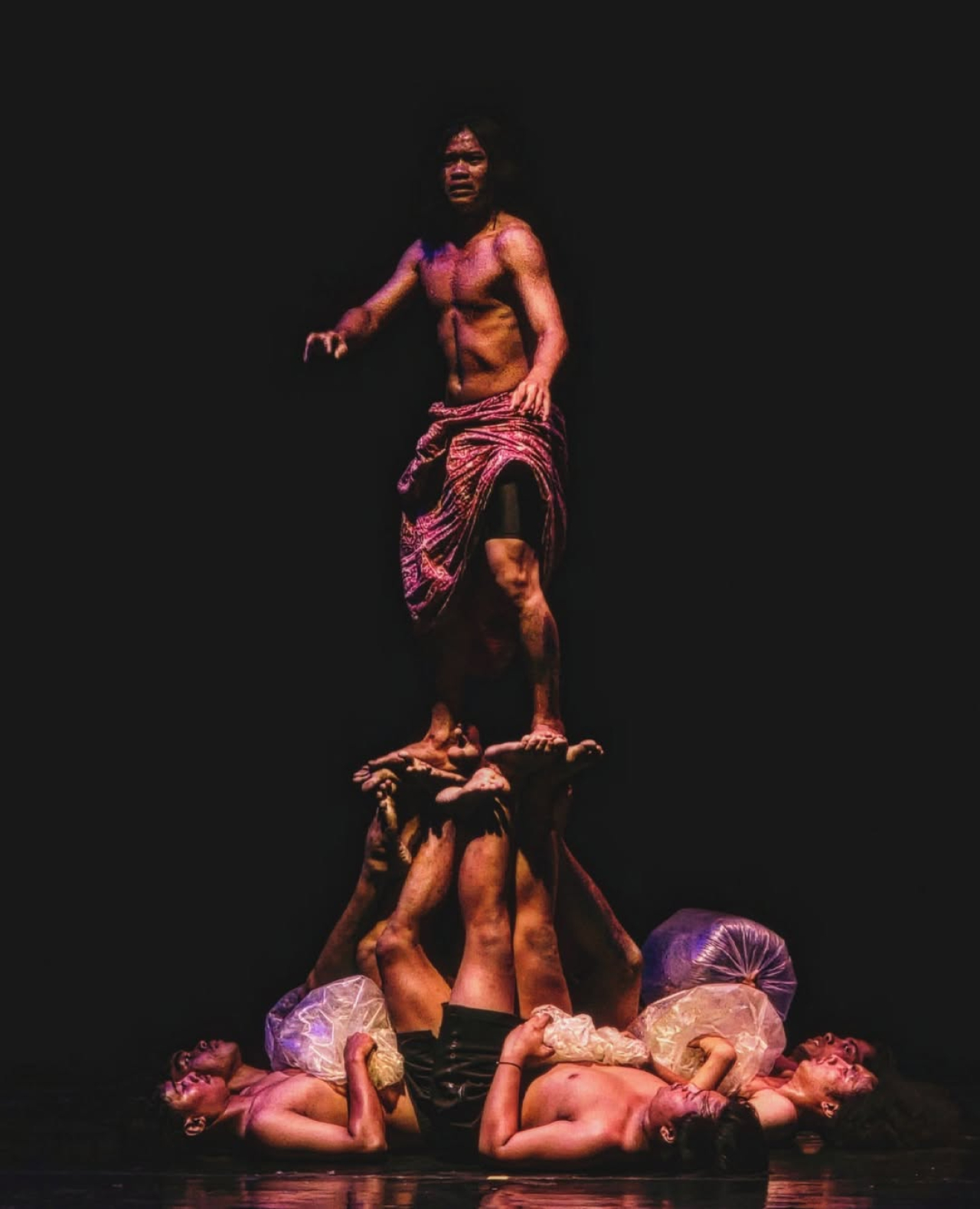 Di atas tubuh-tubuh yang menyangga, seorang manusia berdiri — bukan untuk berkuasa, tapi untuk mencari makna. Dalam gelap panggung, cahaya teater menuntun jiwa kembali pada dirinya sendiri. (Istimewa)