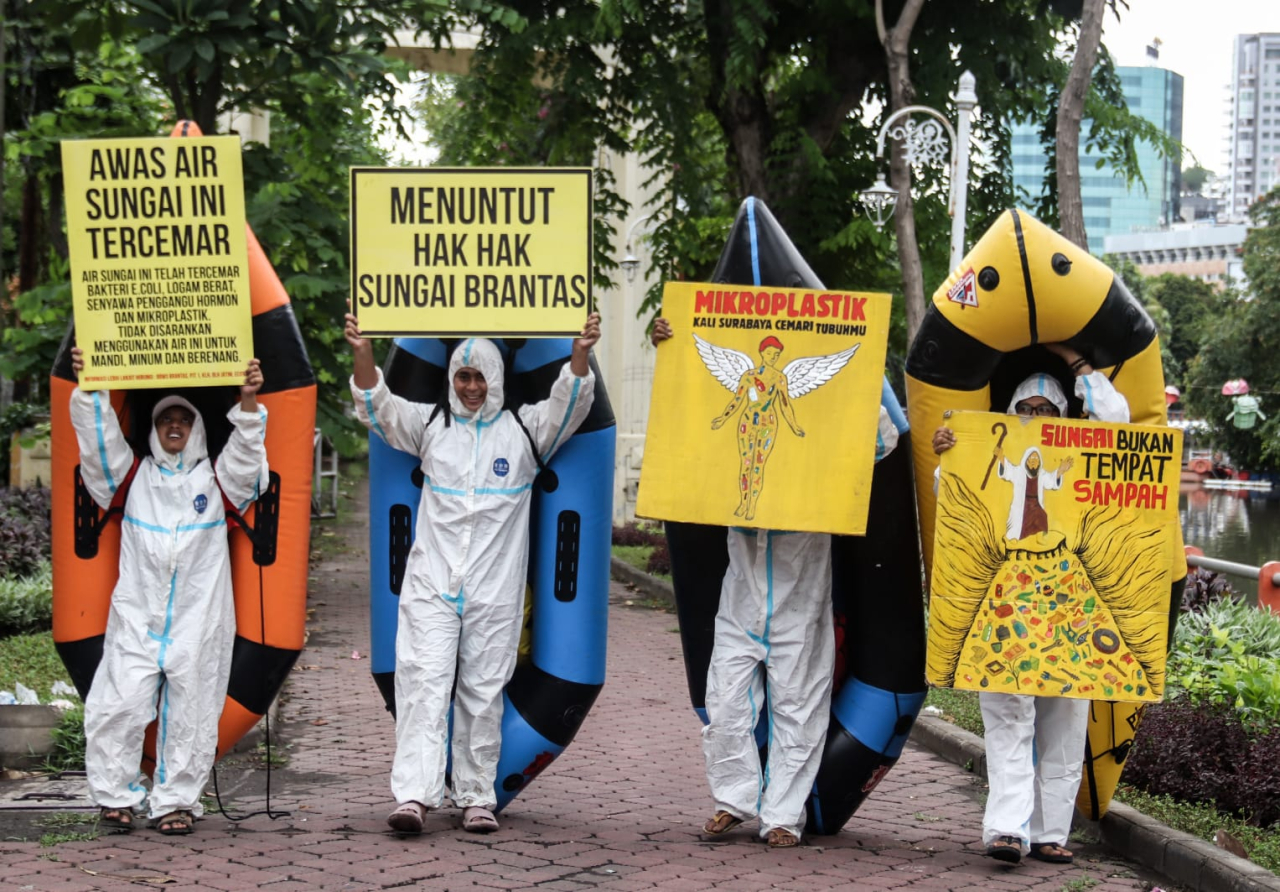 Empat pegiat lingkungan dari Ecoton beraksi di tepi Kali Mas, Surabaya, Senin (3/11/2025). Meski hanya berempat, mereka lantang menuntut pemerintah mengembalikan hak-hak sungai Brantas yang tercemar limbah industri dan mikroplastik. (Robertus Riski)