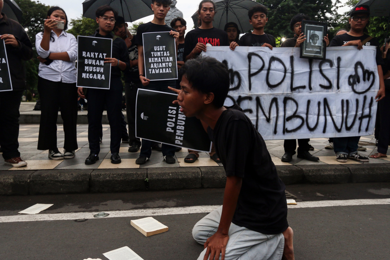 Seorang peserta Aksi Kamisan ke-899 berlutut di depan Gedung Negara Grahadi, Surabaya, menuntut keadilan atas kematian Arianto Tawakal. (Foto: M. Iffan Maulana)
