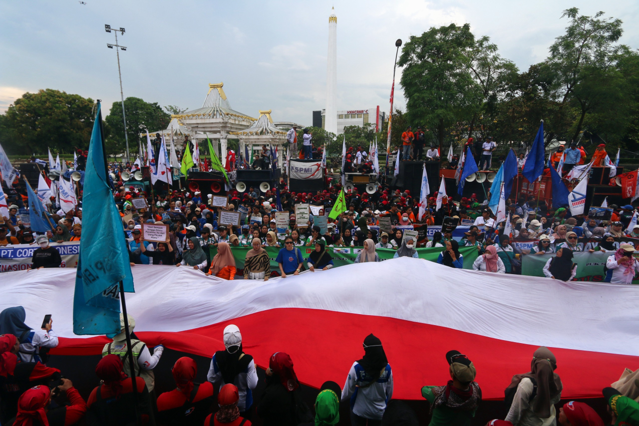 Poster dan bendera diangkat tinggi, menyuarakan tuntutan hak dan keadilan bagi buruh. (Foto: M. Iffan)